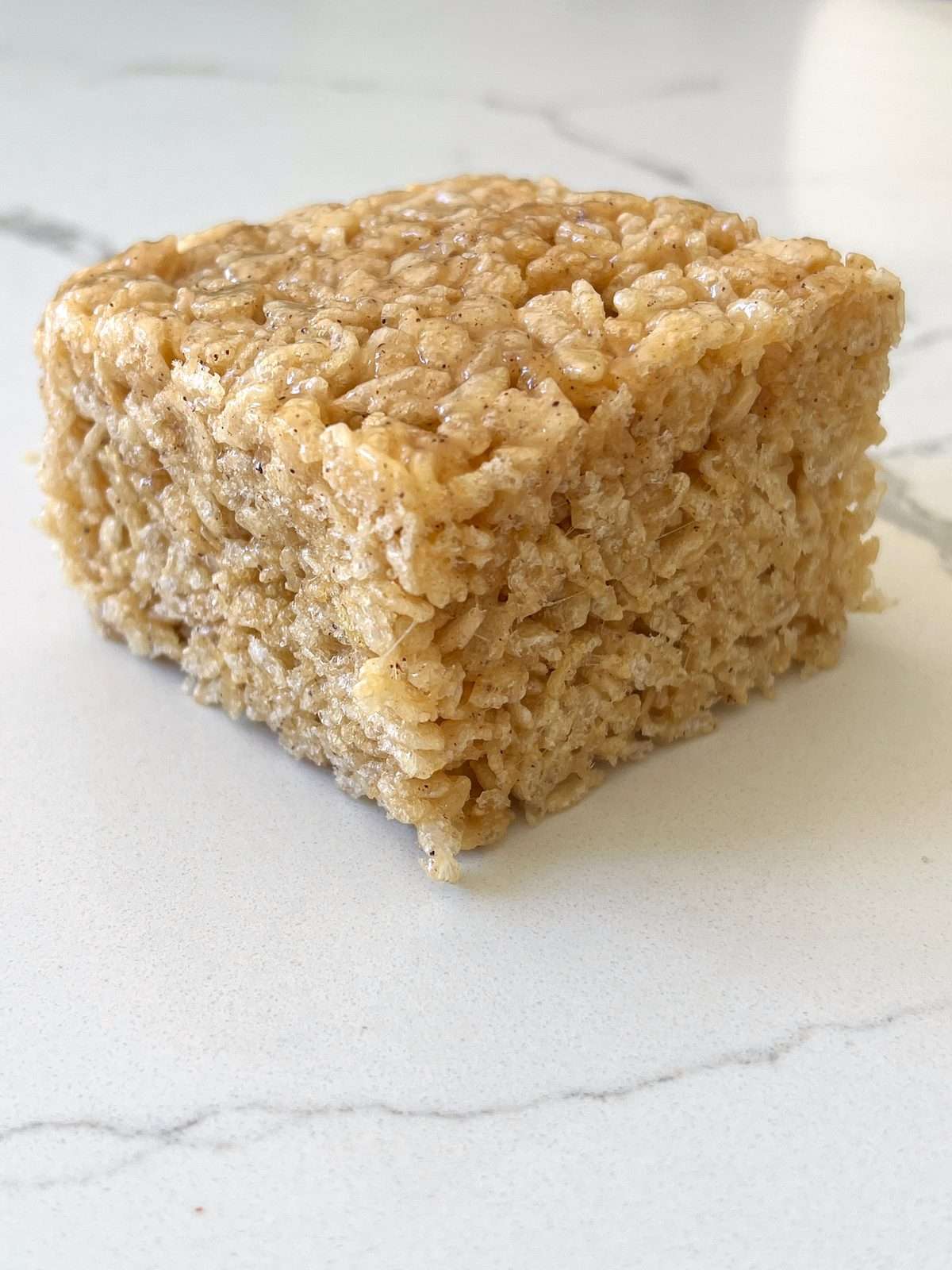 Thick brown butter crispy rice treat on a marble counter