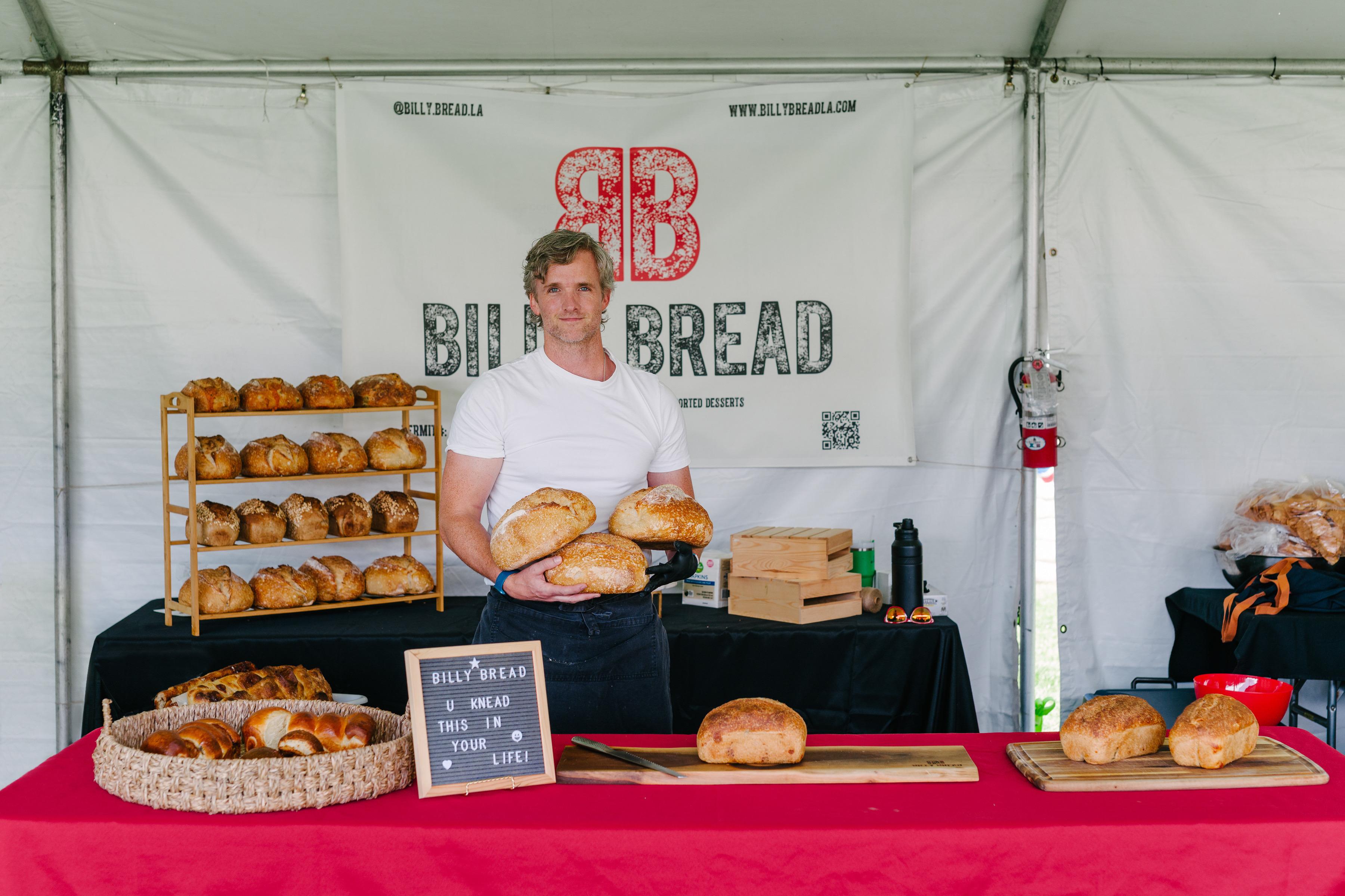 Billy Lush holding an armful of fresh-baked Billy Bread loaves.