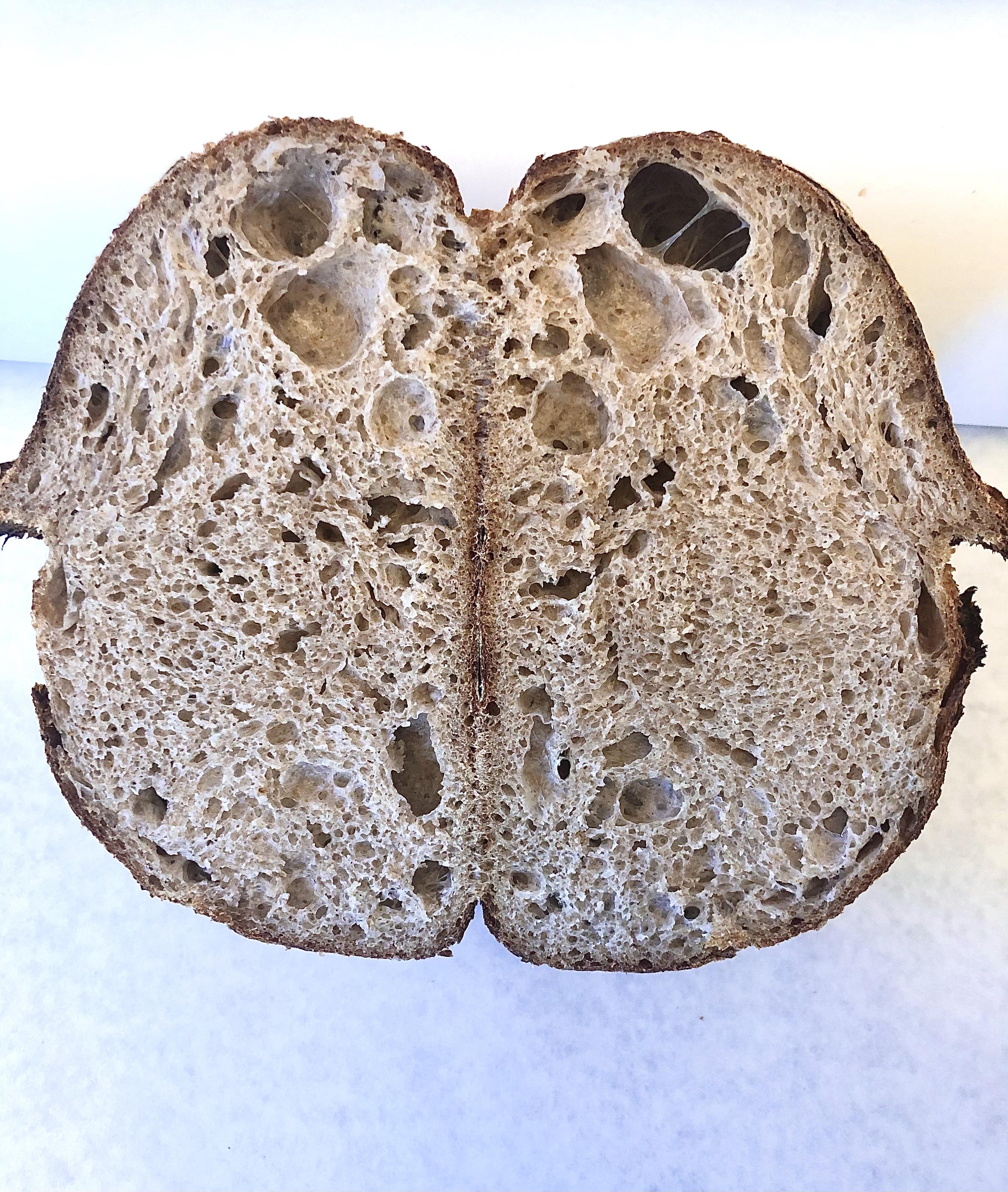 A sliced Billy Bread sourdough loaf showing a dramatic open, airy crumb.